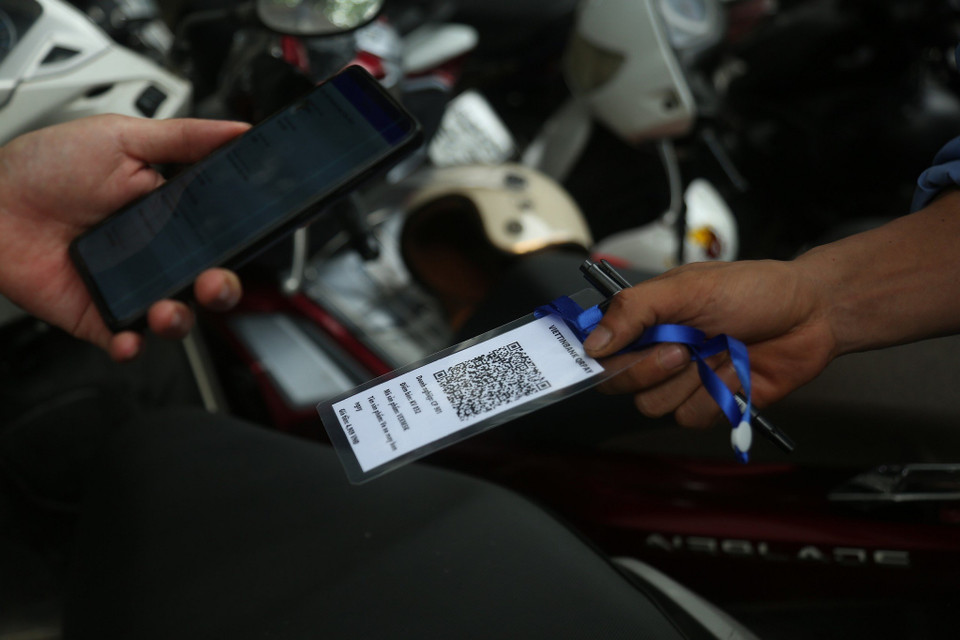 Nhân viên trông giữ xe sẽ đưa mã QR để chủ xe quét mã thanh toán và sau đó hóa đơn sẽ tự động được in ra. (Ảnh: Việt Hùng/Vietnam+)