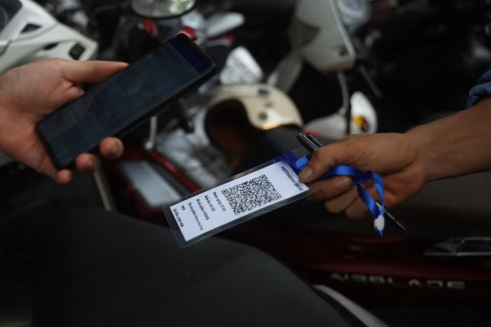 Nhân viên trông giữ xe sẽ đưa mã QR để chủ xe quét mã thanh toán và sau đó hóa đơn sẽ tự động được in ra. (Ảnh: Việt Hùng/Vietnam+)
