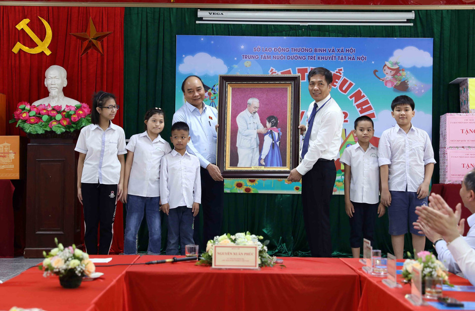 Chủ tịch nước Nguyễn Xuân Phúc tặng bức tranh Chủ tịch Hồ Chí Minh với thiếu nhi cho Trung tâm Nuôi dưỡng trẻ khuyết tật Hà Nội. (Ảnh An Đăng/TTXVN)