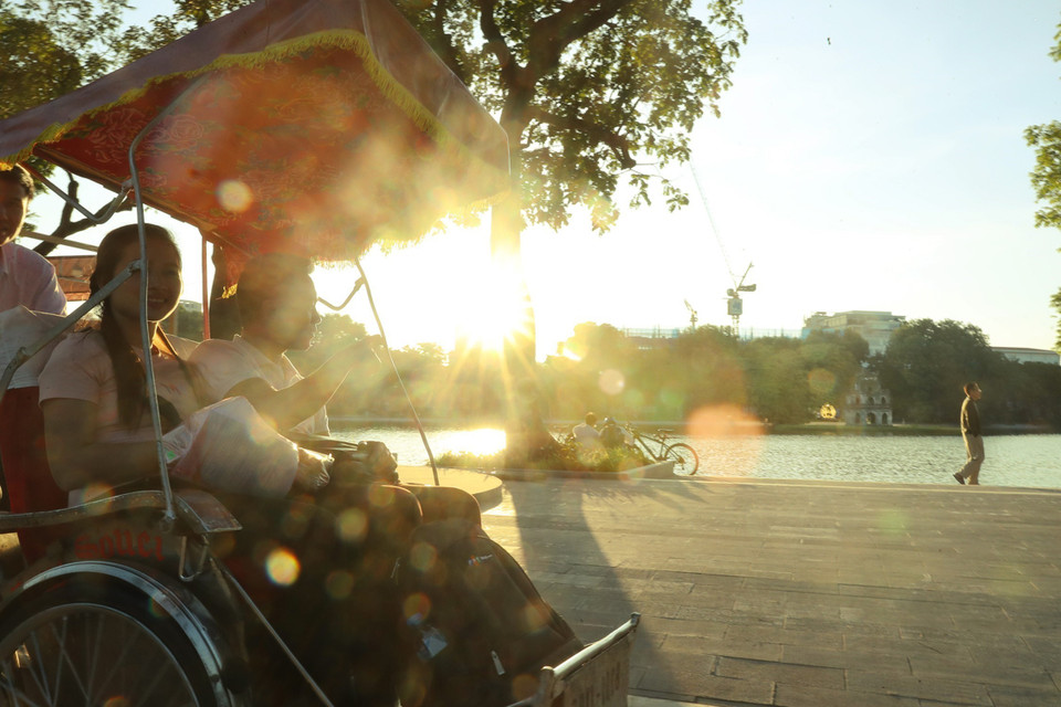 Du khách đi dạo bằng xích lô, ngắm hồ Hoàn Kiếm trong nắng chiều thu. (Ảnh: Lâm Khánh/TTXVN)