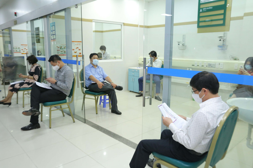 Các cán bộ, nhân viên y tế ngồi giãn cách 30 phút chờ kiểm tra sau tiêm. (Ảnh: Hoàng Hiếu/TTXVN)