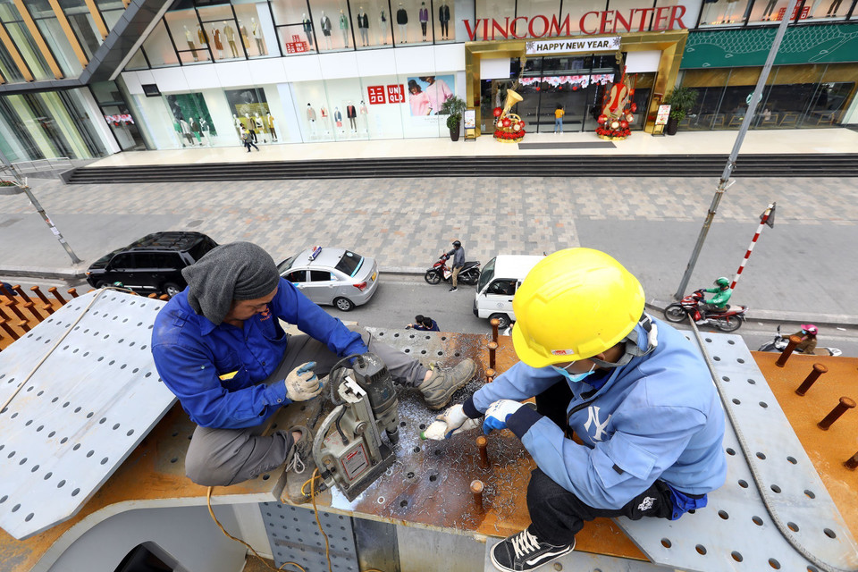 Khoan lỗ để bắt bu lông gia cố dầm cầu. (Ảnh: Huy Hùng/TTXVN)