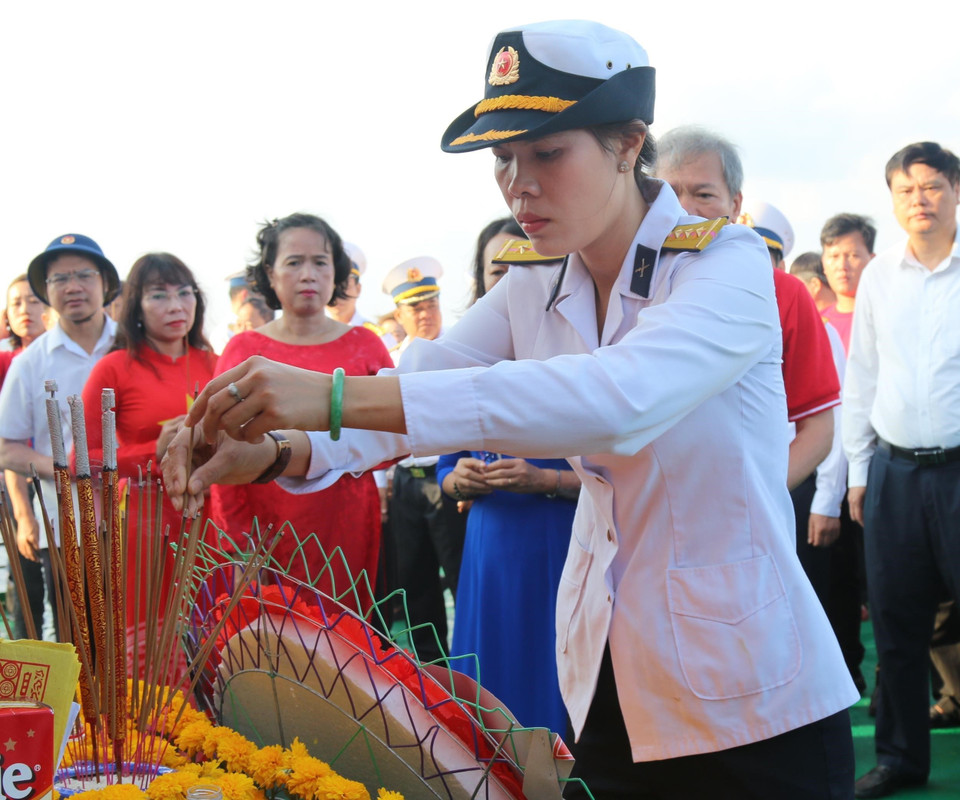 Thượng úy Hải quân Trần Thị Thủy (con gái liệt sỹ, Anh Hùng lực lượng vũ trang Trần Văn Phương hy sinh trên quần đảo Trường Sa) xúc động thắp hương tưởng niệm các liệt sỹ hy sinh trên quần đảo Trường Sa. (Ảnh: Sỹ Tuyên/TTXVN)