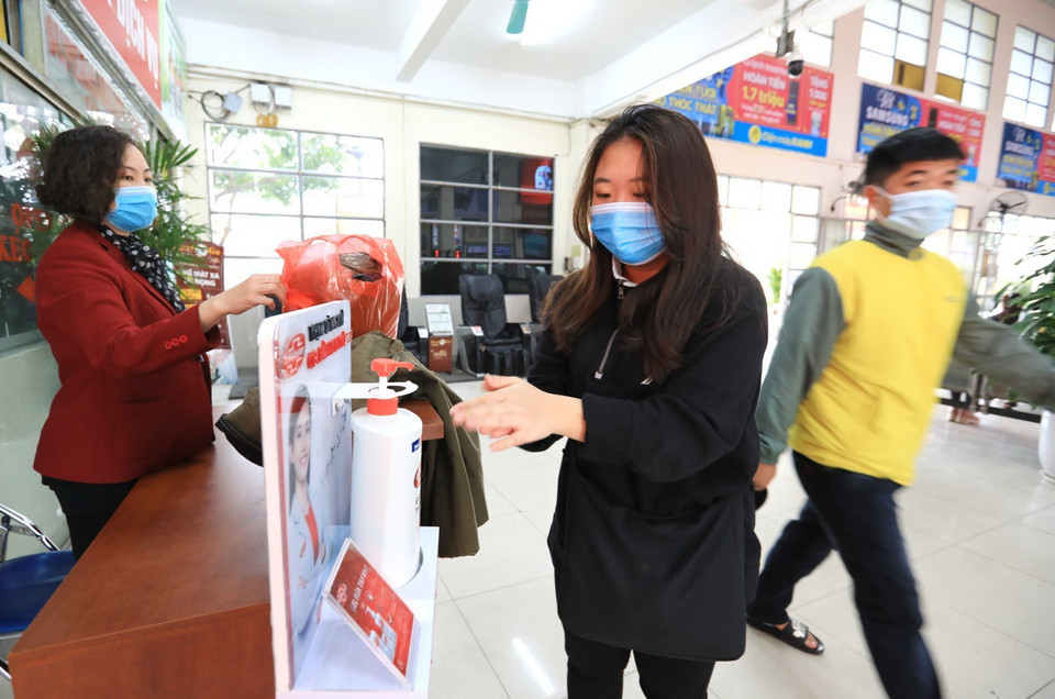 Người dân rửa tay sát khuẩn trước khi lên xe tại bến xe Mỹ Đình. (Ảnh: Thành Đạt/TTXVN)