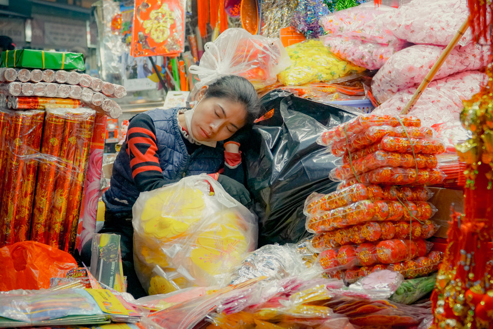 Một chủ cửa hàng chợp mắt để lấy sức cho một ngày dài bán hàng. (Ảnh: Minh Hiếu/Vietnam+)