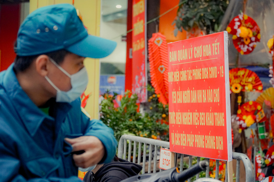 Trong bối cảnh phức tạp của dịch COVID-19, quận Hoàn Kiếm yêu cầu các phường trên địa bàn bố trí lực lượng ứng trực tại các cổng ra vào khu vực chợ hoa Tết, thực hiện đo thân nhiệt, yêu cầu người ra vào khu vực chợ hoa Tết phải đeo khẩu trang, rửa tay bằng dung dịch sát khuẩn nhằm đảm bảo an toàn cho người dân trước tình hình dịch COVID-19 đang lây lan. (Ảnh: Minh Hiếu/Vietnam+)