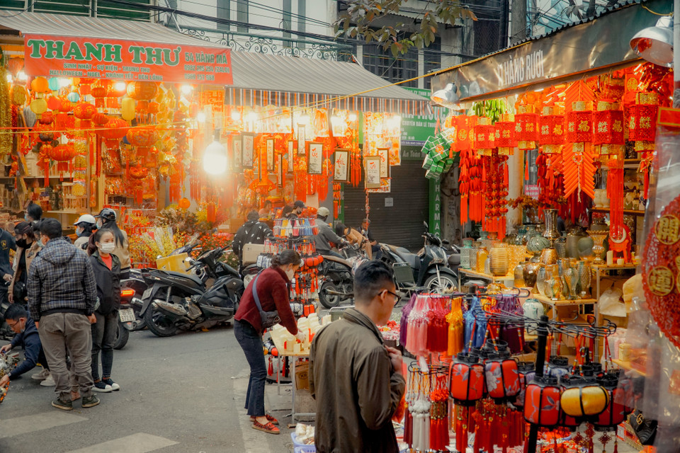 Chia sẻ với phóng viên, chị Thu Huyền (chủ cửa hàng 54 Hàng Mã) cho biết giá cả của các mặt hàng trang trí năm nay không có nhiều biến động. Các sản phẩm câu đối treo có kích thước lớn có giá khoảng từ 300-400 nghìn đồng. Những chiếc mành treo nhỏ trang trí cây đào hay những dây đồng tiền vàng có giá dao động từ 8.000-30.000 đồng. (Ảnh: Minh Hiếu/Vietnam+)