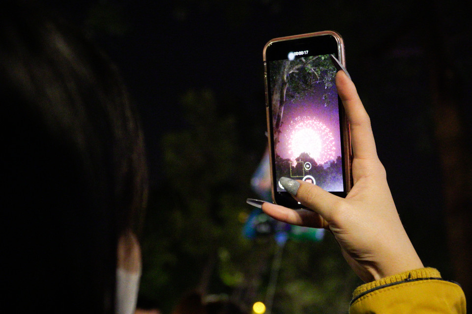 Nhiều người ghi lại khoảnh khắc pháo hoa bằng điện thoại. (Ảnh: Minh Hiếu/Vietnam+)