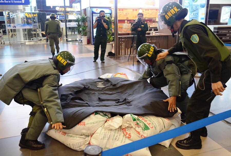 Nhân viên an ninh cơ động dùng chăn hạn chế sức công phá bom, mìn phủ lên chiếc valy có chứa chất nổ TNT. (Ảnh: Việt Hùng/Vietnam+)