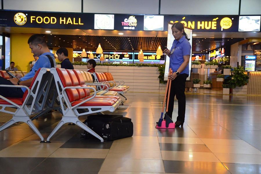 Nhân viên vệ sinh nhà ga đang làm việc phát hiện chiếc valy không xác định được chủ để tại dưới gầm ghế ngồi nhà ga hành khách sân bay Nội Bài. (Ảnh: Việt Hùng/Vietnam+)