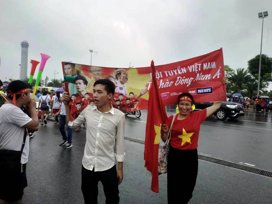 Băng rôn, cờ đỏ sao vàng, áo đồng phục “nhuốm đỏ” cả một đoạn đường dọc sân bay, nơi xe chở các cầu thủ Olympic Việt Nam đi qua. (Ảnh: PV/Vietnam+)