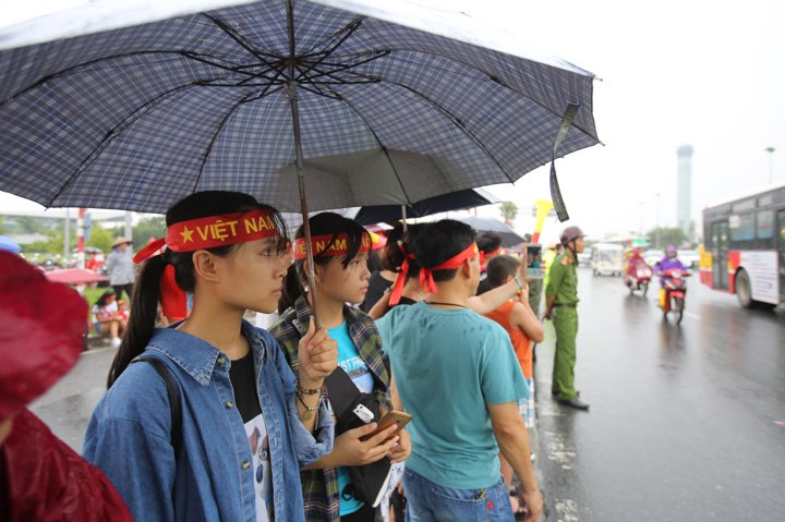 Một số người kiên nhẫn cầm ô đứng trong mưa, chờ được gặp cầu thủ Olympic Việt Nam. (Ảnh: PV/Viettnam+)