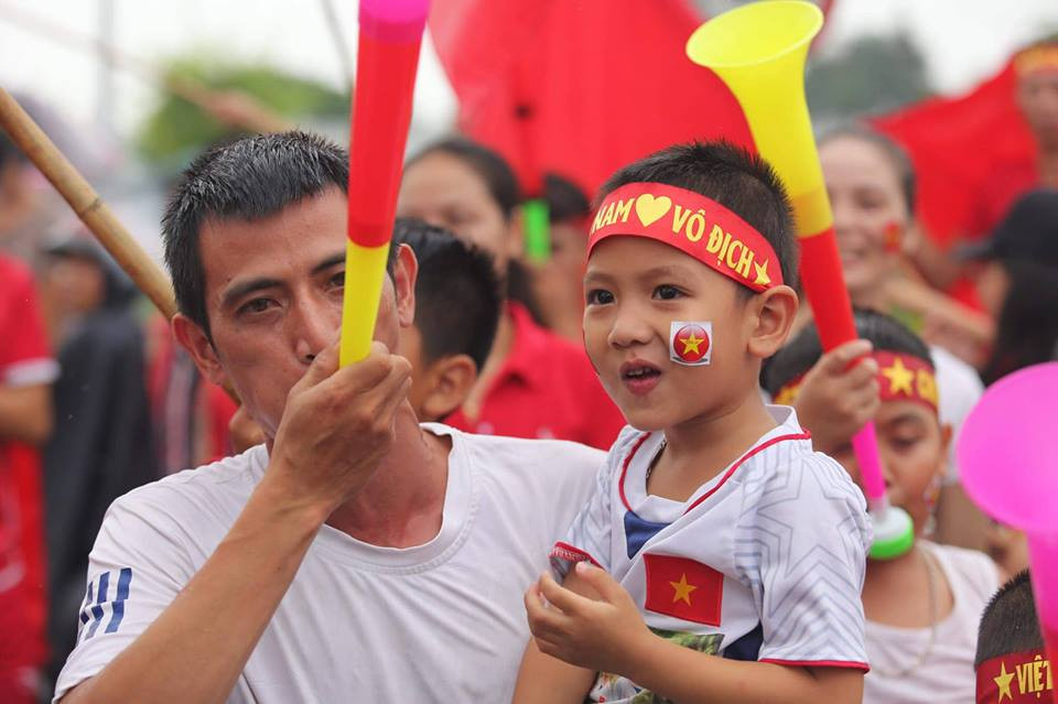 Nhiều cổ động viên nhí được bố mẹ và gia đình ‘cõng” theo để chào đón đội tuyển Olympic Việt Nam đặt chân xuống sân bay Nội Bài sau thành tích lọt vào top 4 tại ASIAD 2018 tại Indonesia. (Ảnh: PV/Vietnam+)