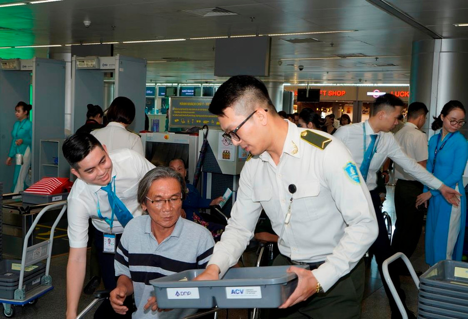 Nhân viên kiểm tra an ninh hỗ trợ, giúp đỡ nhiệt tình các thương binh nặng khi qua cửa kiểm soát an ninh. (Ảnh: Anh Tuấn/Vietnam+)
