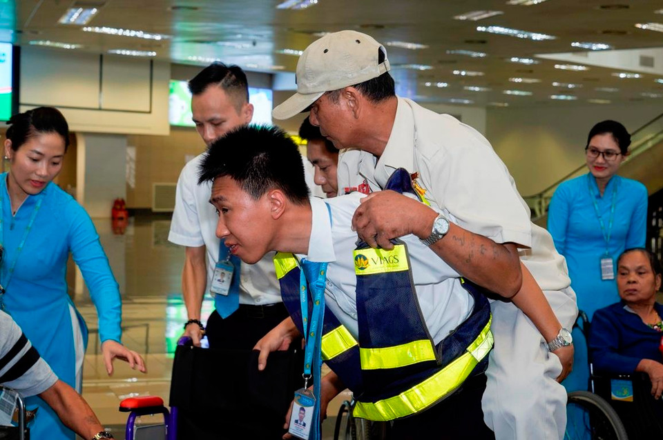 Thậm chí, một số nhân viên mặt đất phải cõng các thương binh nặng ra xe lăn để dễ di chuyển. (Ảnh: Anh Tuấn/Vietnam+)