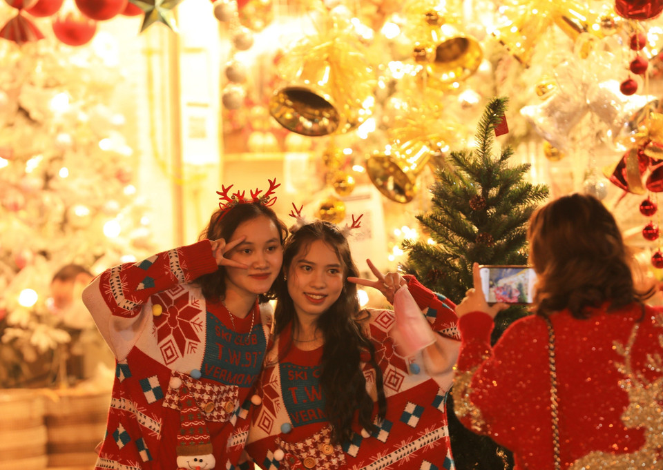 Một số bạn trẻ cởi bỏ khẩu trang để chụp hình, không đảm bảo phòng, chống dịch khi vui chơi trên phố Hàng Mã (ảnh chụp tối 20/12). (Ảnh: Hoàng Hiếu/TTXVN)