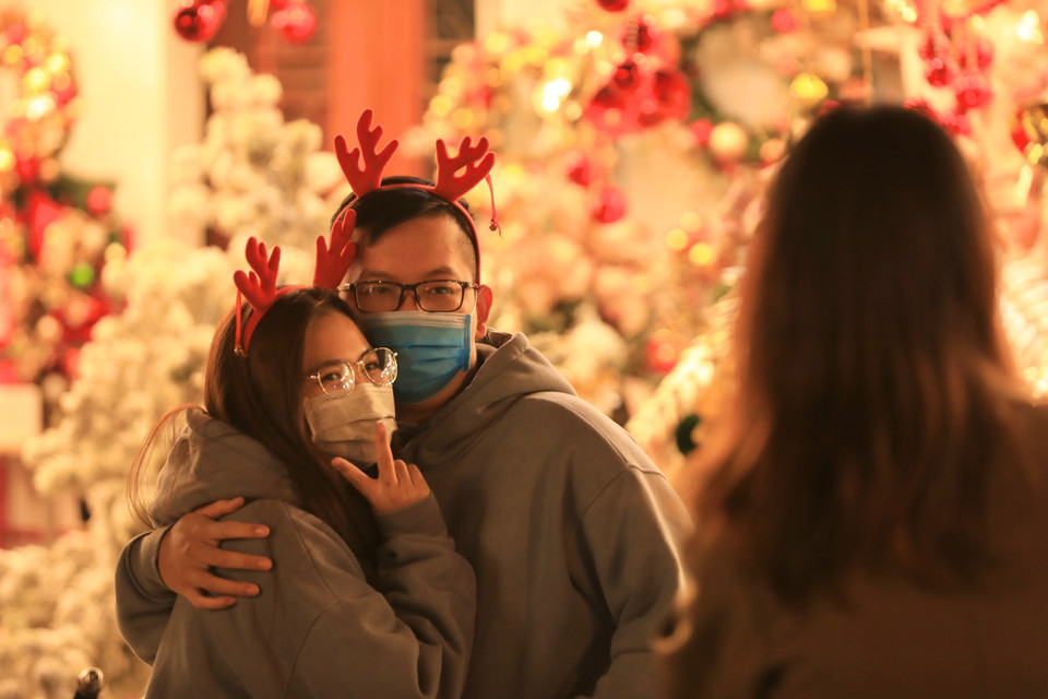 Nhiều bạn trẻ chụp ảnh để lưu giữ kỷ niệm Giáng sinh 2021 trên phố Hàng Mã. (Ảnh: Hoàng Hiếu/TTXVN)