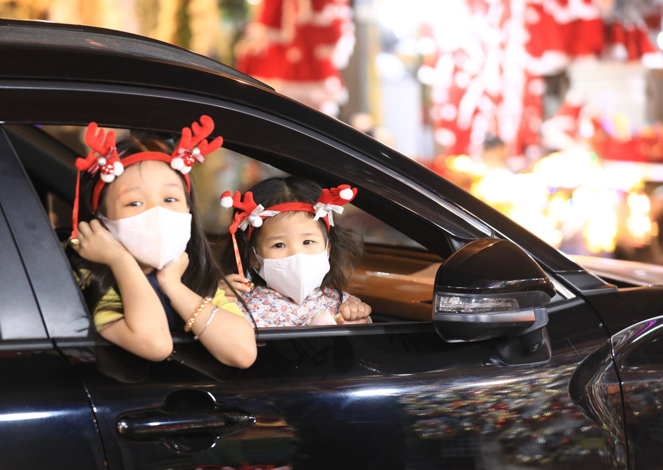 Các em bé được bố mẹ đưa đi mua sắm, vui chơi trên phố Hàng Mã tối 20/12. (Ảnh: Hoàng Hiếu/TTXVN)