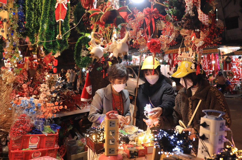 Người dân mua sắm đồ Giáng sinh 2021 trên phố Hàng Mã tối 20/12. (Ảnh: Hoàng Hiếu/TTXVN)