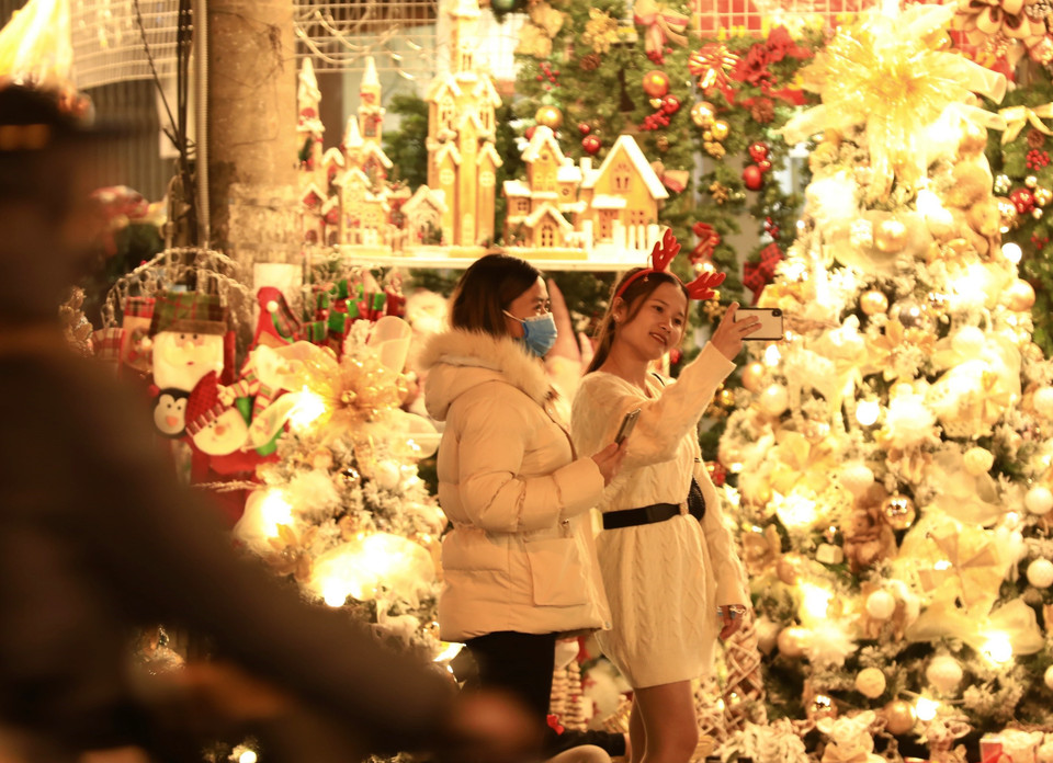 Một số bạn trẻ cởi bỏ khẩu trang để chụp hình, không đảm bảo phòng, chống dịch khi vui chơi trên phố Hàng Mã (ảnh chụp tối 20/12). (Ảnh: Hoàng Hiếu/TTXVN)