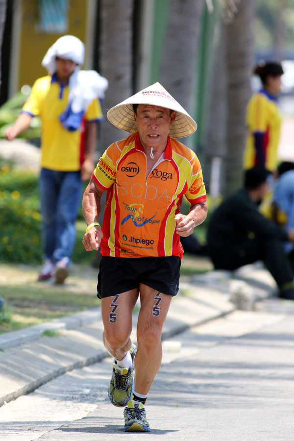 Một vận động viên nước ngoài đội nón lá Việt Nam để chống chọi cái nắng oi ả. (Ảnh: Hiền Trần/Vietnam+)