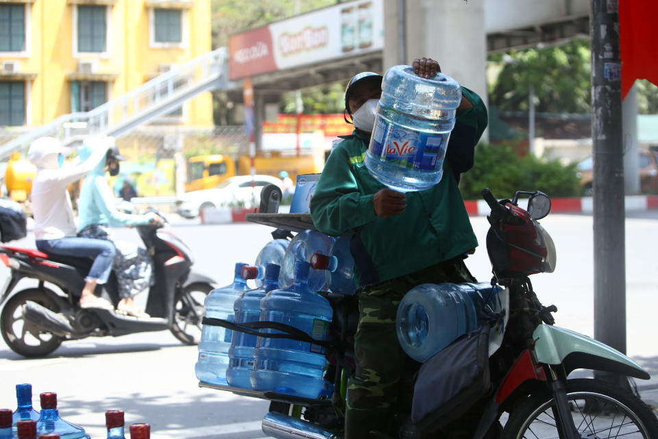 Các đại lý nước sạch đóng bình bận rộn giao hàng giữa cái nóng gay gắt của trưa hè. (Ảnh: Minh Quyết/TTXVN)