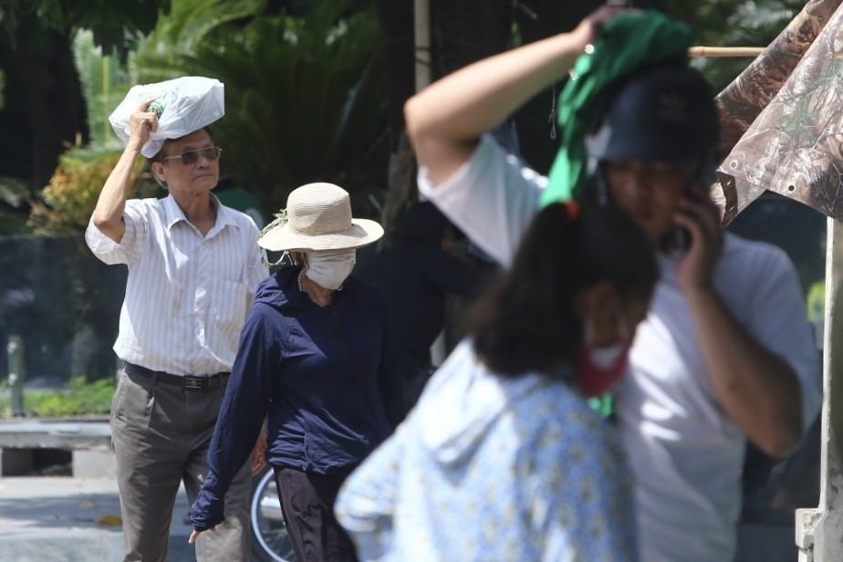 Người dân tìm chỗ trú nắng trước cái nóng gay gắt của những ngày đầu mùa hè. (Ảnh: Minh Quyết/TTXVN)