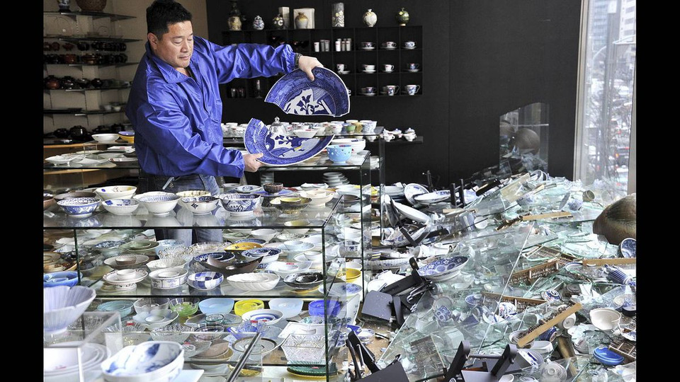 Chủ một cửa hàng gốm sứ kiểm tra đồ đạc bị hư hỏng sau trận động đất mạnh 8,9 độ. (Nguồn: theglobeandmail)