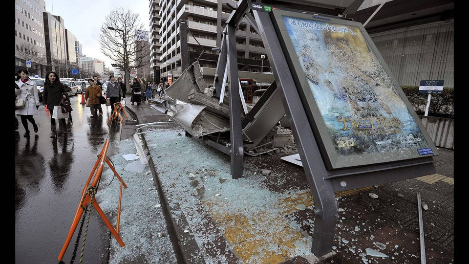 Người dân đi bộ qua một trạm xe buýt đổ nát ở Sendai, tỉnh Miyagi, Nhật Bản. (Nguồn: theglobeandmail)