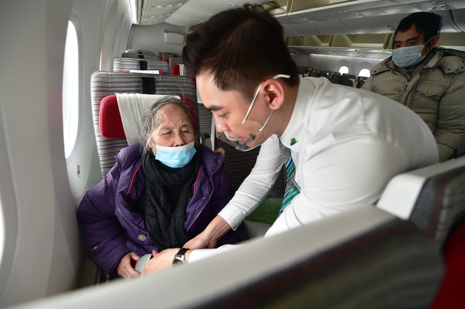 Thắt dây an toàn giúp một hành khách người cao tuổi trên chuyến bay từ Ba Lan về nước. (Ảnh: CTV/Vietnam+)