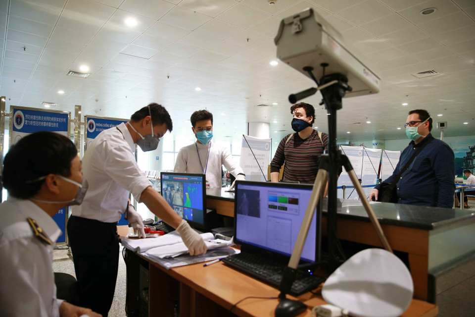  Lực lượng y tế kiểm tra thân nhiệt đối với hành khách nhập cảnh. (Ảnh: Doãn Tấn/TTXVN)