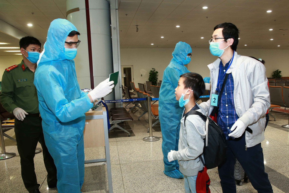 Lực lượng Công an cửa khẩu kiểm tra hộ chiếu, hướng dẫn hành khách đi cách ly. (Ảnh: Doãn Tấn/TTXVN)