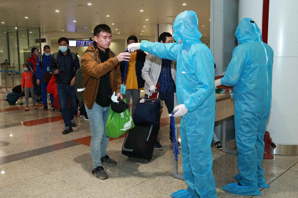 Lực lượng Công an cửa khẩu Cảng hàng không Quốc tế Nội Bài kiểm tra hộ chiếu, hướng dẫn và phát thẻ cho hành khách đi cách ly. (Ảnh: Doãn Tấn/TTXVN)