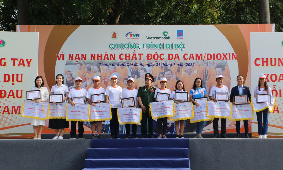 Đại diện Ban tổ chức tặng cờ và biểu trưng cho các đơn vị tài trợ chương trình đi bộ đồng hành Vì nạn nhân chất độc da cam/dioxin. (Ảnh: Thanh Vũ/TTXVN)
