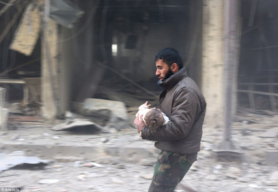 Người đàn ông bế một em bé bị thương trong trận không kích ở Ghouta. (Nguồn: Anadolu)