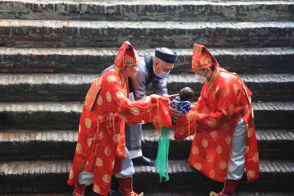 Các cụ trong đoàn tế lấy nước tại Đền Cùng giếng ngọc về thờ. (Ảnh: Thanh Thương/TTXVN)