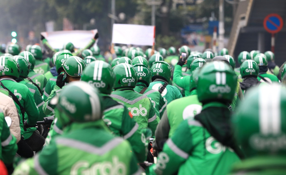 Các tài xế Grab với những băngrôn khẩu hiệu 'Grab thu thuế VAT bất hợp lý'.(Ảnh: Thành Đạt/TTXVN)