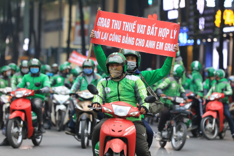 Các tài xế Grab với những băngrôn khẩu hiệu 'Grab thu thuế VAT bất hợp lý'.(Ảnh: Thành Đạt/TTXVN)