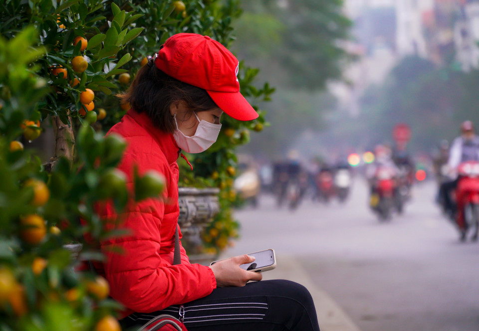 Một số tiểu thương do ế khách nên chỉ biết ngồi lướt điện thoại để giết thời gian. (Ảnh: Minh Hiếu/Vietnam+)