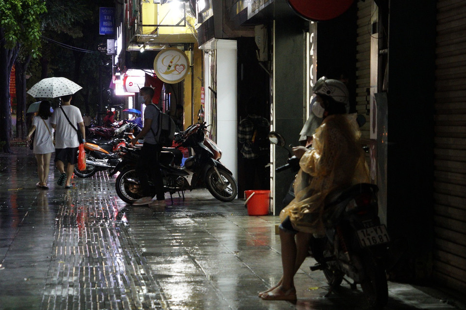 Để đảm bảo an toàn cho bản thân trong mưa lớn tránh và ùn tắc, một số người dân chọn cách dừng đỗ và trú mưa tại nơi an toàn. (Ảnh: Minh Hiếu/Vietnam+)