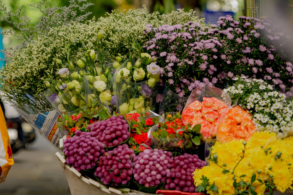 Giữa Hà Nội ồn ào như thế nhưng chỉ một gánh hàng hoa thôi cũng đủ kéo lòng người về miền ký ức xa xôi đầy kỉ niệm. (Ảnh: Minh Hiếu/Vietnam+)