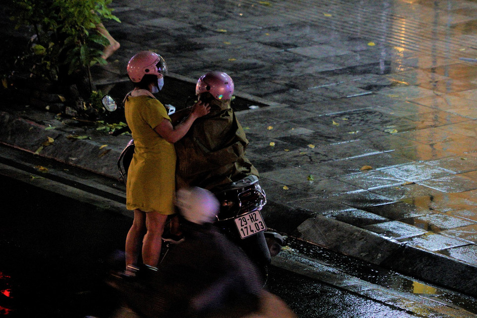 Cơn mưa to bất chợt dần khiến người dân phải dừng lại để mặc áo mưa. (Ảnh: Minh Hiếu/Vietnam+) 