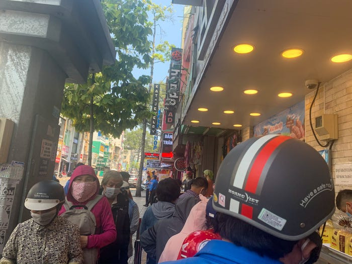 Một hàng dài người xếp hàng chờ mua bánh, hầu hết đều đeo khẩu trang. (Nguồn: businessinsider.com)