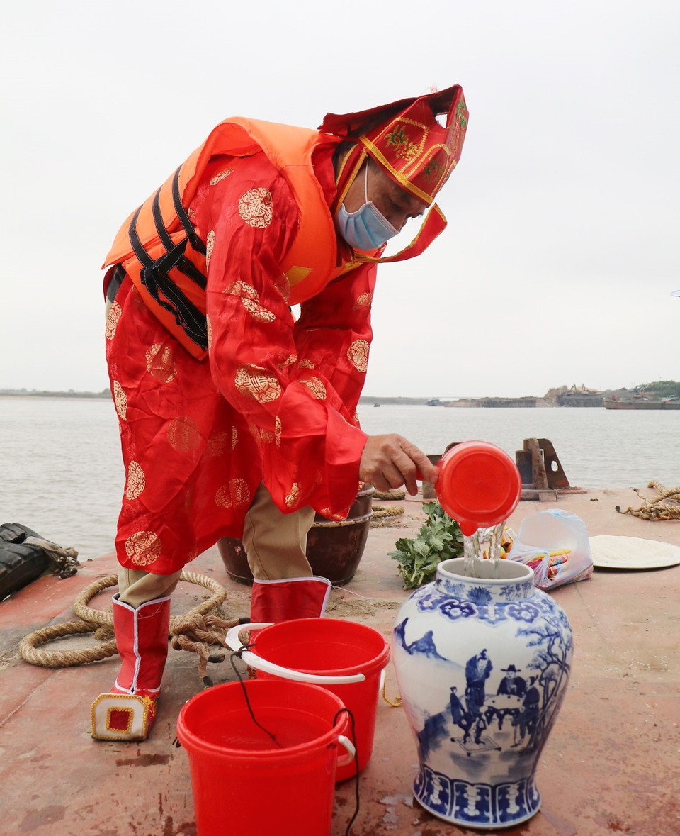 Chủ tế - ông Nguyễn Trọng Thủy, thực hiện nghi lễ lấy nước thiêng tại ngã ba sông. (Ảnh: Trung Kiên/TTXVN)