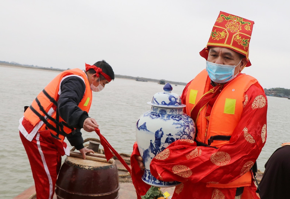 Sau khi lấy xong nước, chủ tế là người trực tiếp ôm giữ âu gốm đựng nước thiêng đến khi lên bờ. (Ảnh: Trung Kiên/TTXVN)