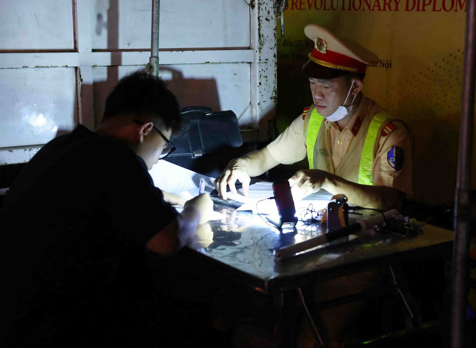 Cán bộ, chiến sỹ thuộc tổ công tác liên ngành Y1/141 lập biên bản xử lý 1 trường hợp vi phạm trật tự an toàn giao thông. (Ảnh: Phạm Kiên /TTXVN)