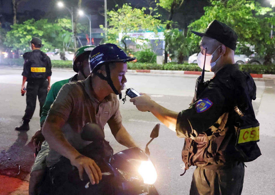 Cán bộ, chiến sỹ thuộc tổ công tác liên ngành Y6/141 kiểm tra nồng độ cồn với người tham gia giao thông. (Ảnh: Phạm Kiên/TTXVN)