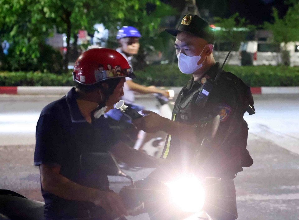 Cán bộ, chiến sỹ thuộc tổ công tác liên ngành Y6/141 kiểm tra nồng độ cồn với người tham gia giao thông. (Ảnh: Phạm Kiên/TTXVN)