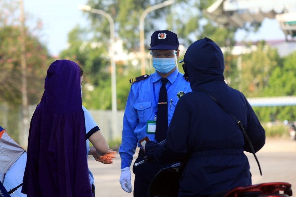 Lực lượng bảo vệ kiểm tra việc đeo khẩu trang và rửa tay sát khuẩn từng công nhân trước khi vào công ty làm việc. (Ảnh: Phan Tuấn Anh/TTXVN)