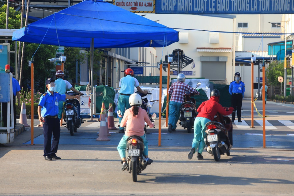 Lực lượng bảo vệ Công ty TOTO Việt Nam hướng dẫn công nhân đi theo làn đường quy định trước khi vào công ty. (Ảnh: Phan Tuấn Anh/TTXVN)